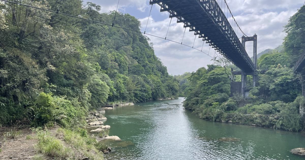 深い緑の山あいを流れる川と、川にかかる吊り橋