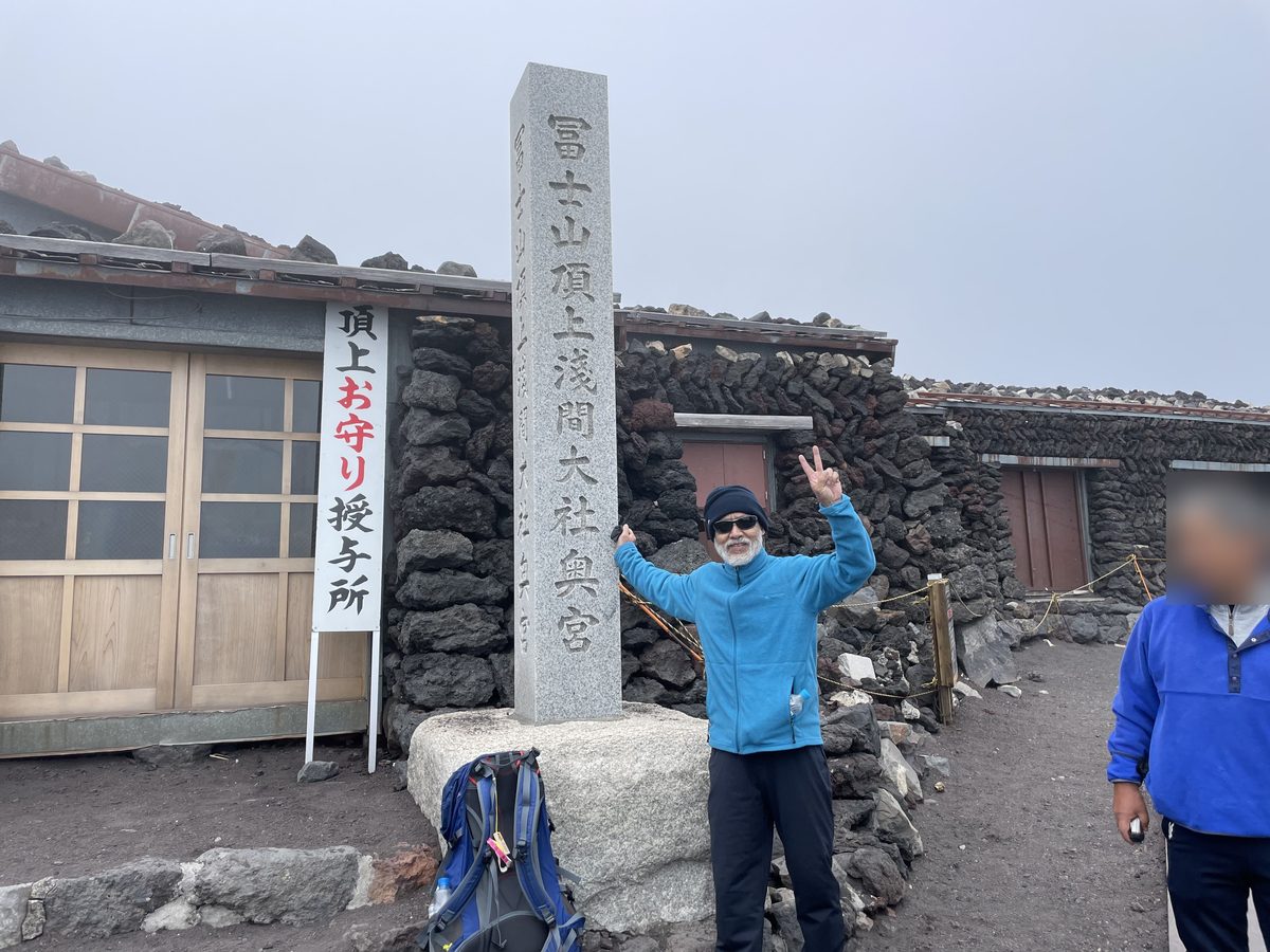 富士山頂上浅間大社奥宮の石碑の前に立つ筆者（65歳当時）