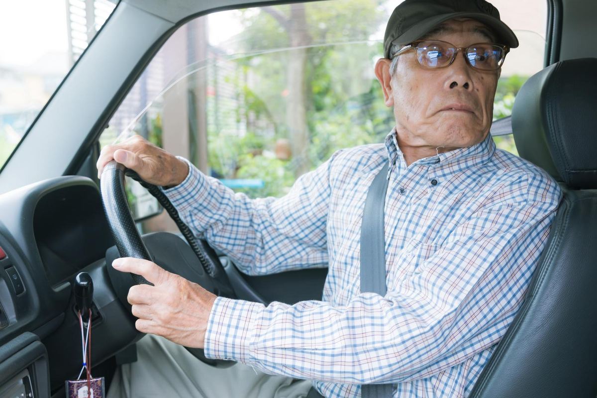運転席でバック中に後ろを確認する高齢の男性