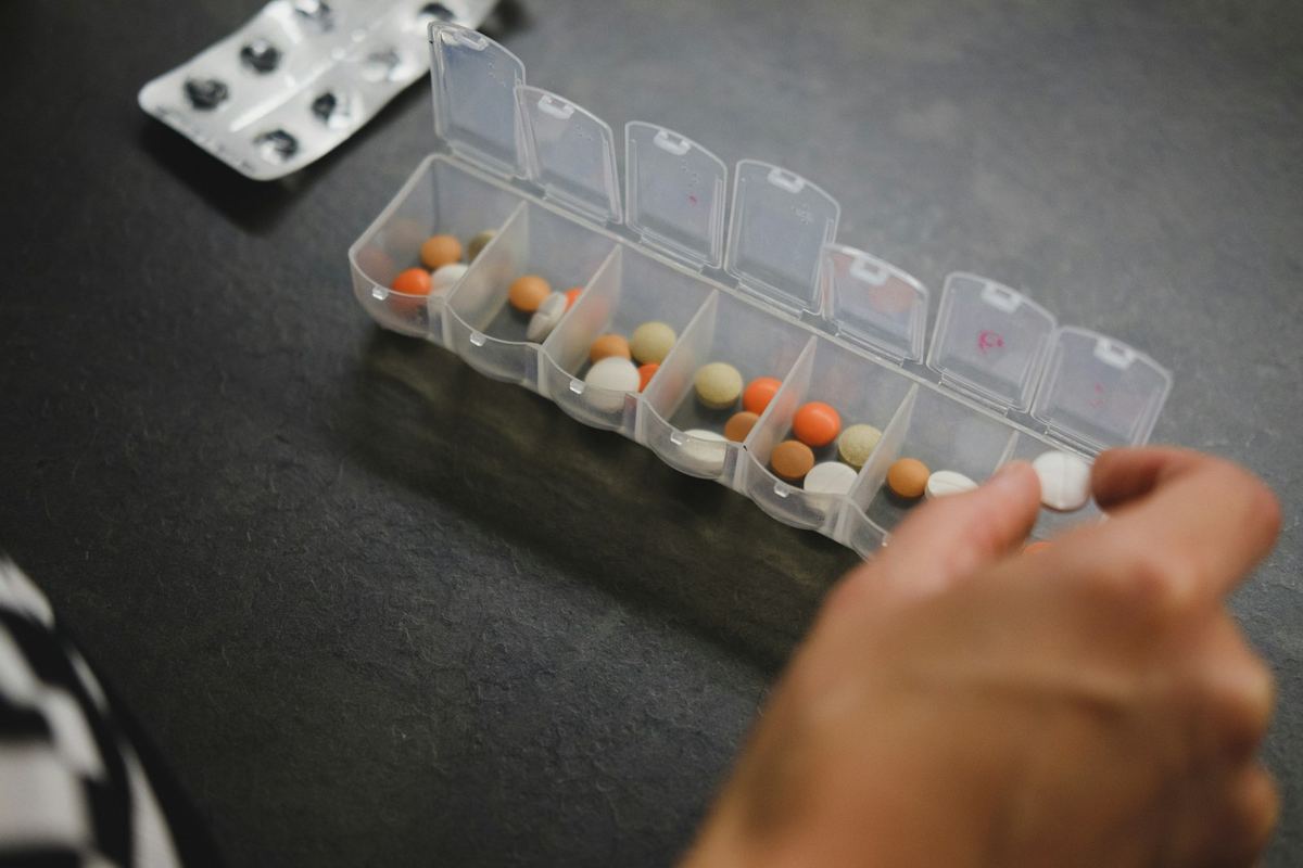 薬の仕分けケースから錠剤を取る手