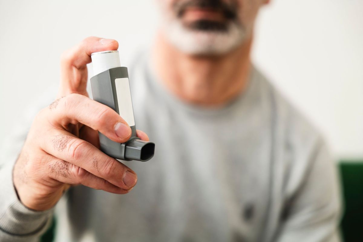 喘息の吸入器を手に持つ年配の男性