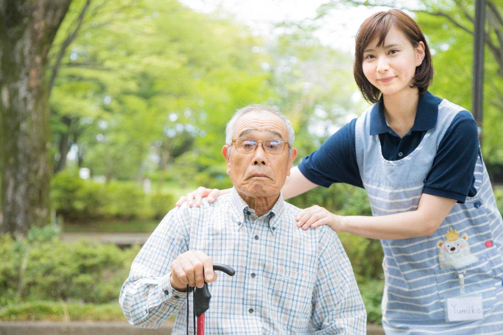 公園で車椅子の高齢男性と介護士